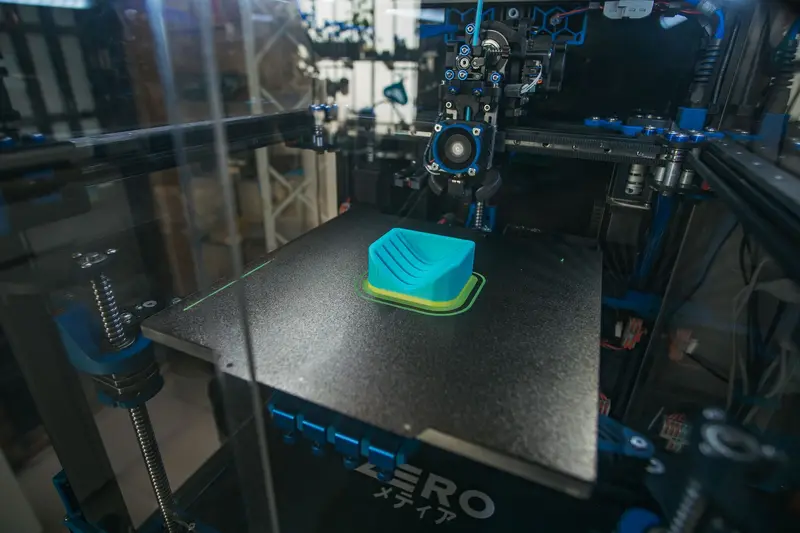 3D printer building a green object on its print bed