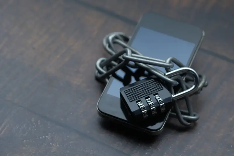 Smartphone wrapped in chains and locked with a combination padlock