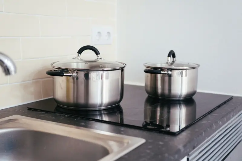 Two stainless steel pots on the black surface of an induction cooktop