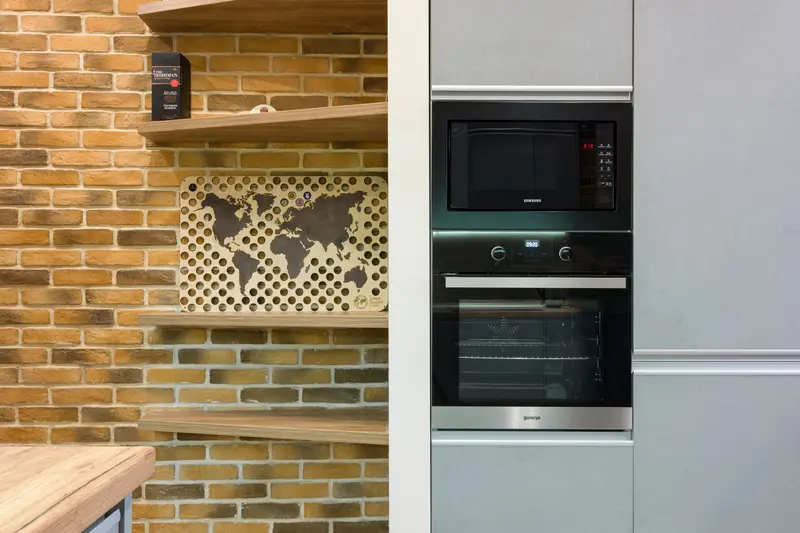Built-in microwave oven in a kitchen with a brick wall