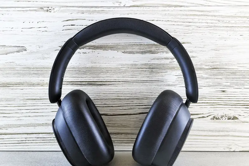 Dark over-ear headphones resting on a light wooden surface