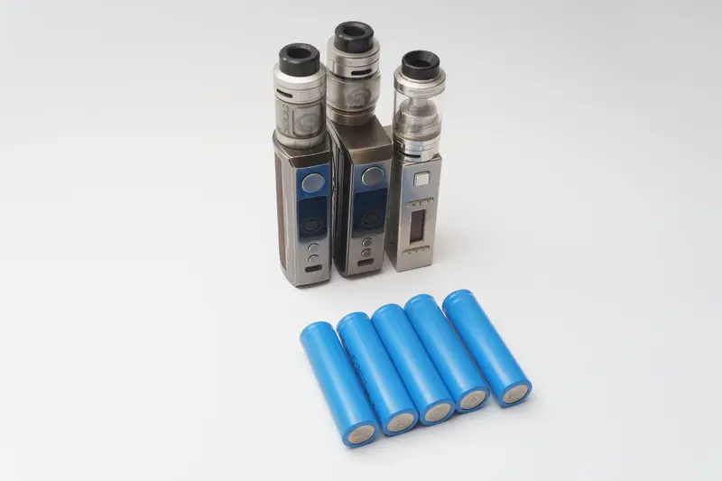 Blue cylindrical lithium-ion battery cells next to electronic devices