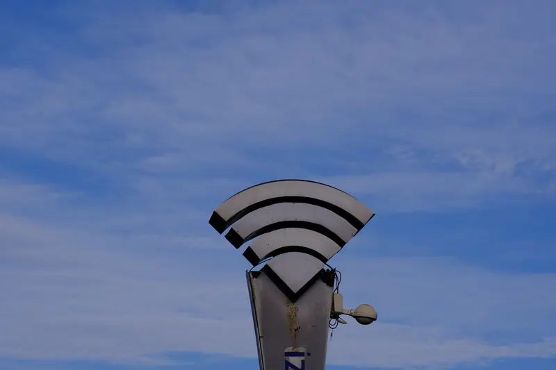 Wi-Fi symbol shaped like curved arcs on a pole against a blue sky
